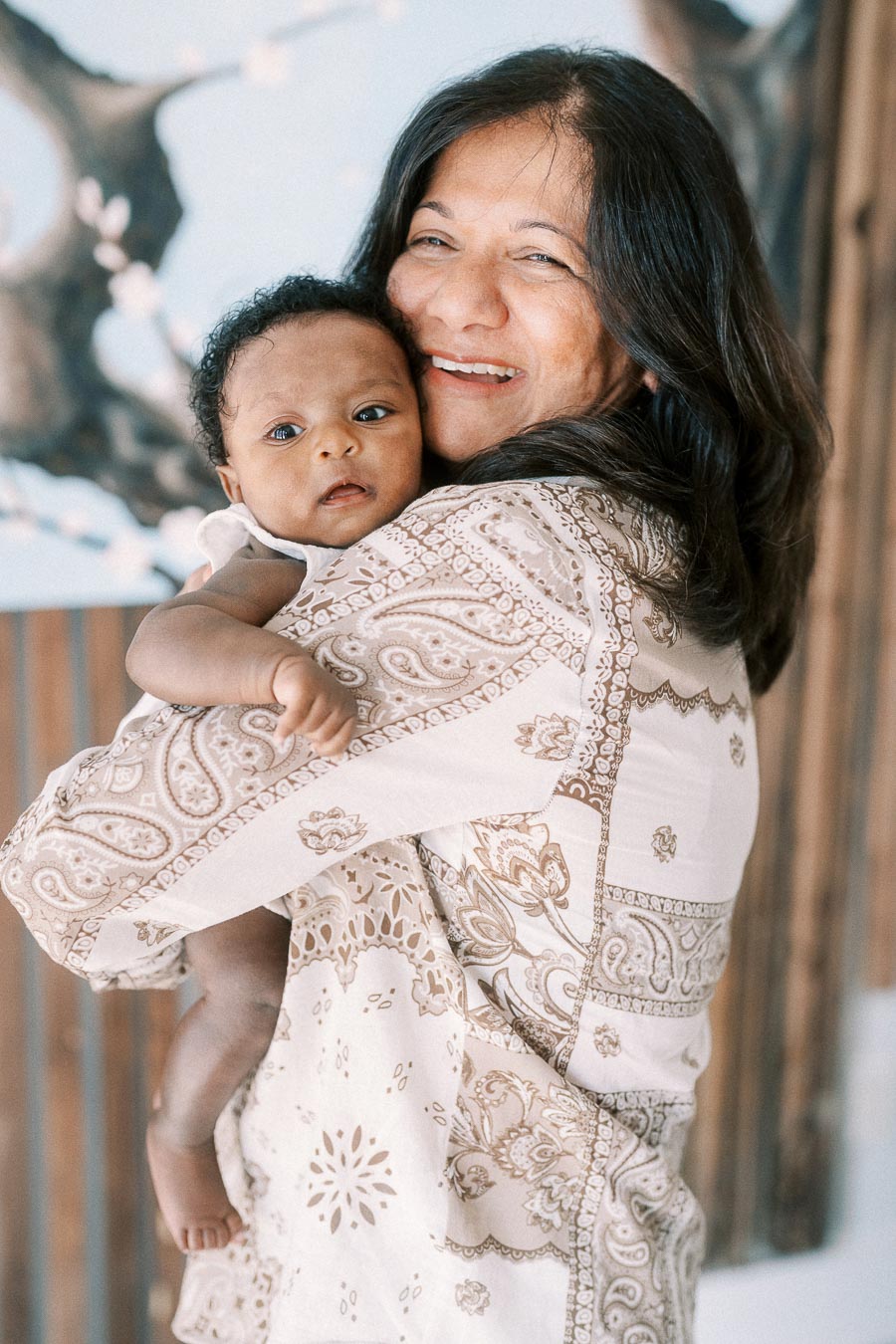 Karina smiling while holding baby Isabella against her shoulder at home.