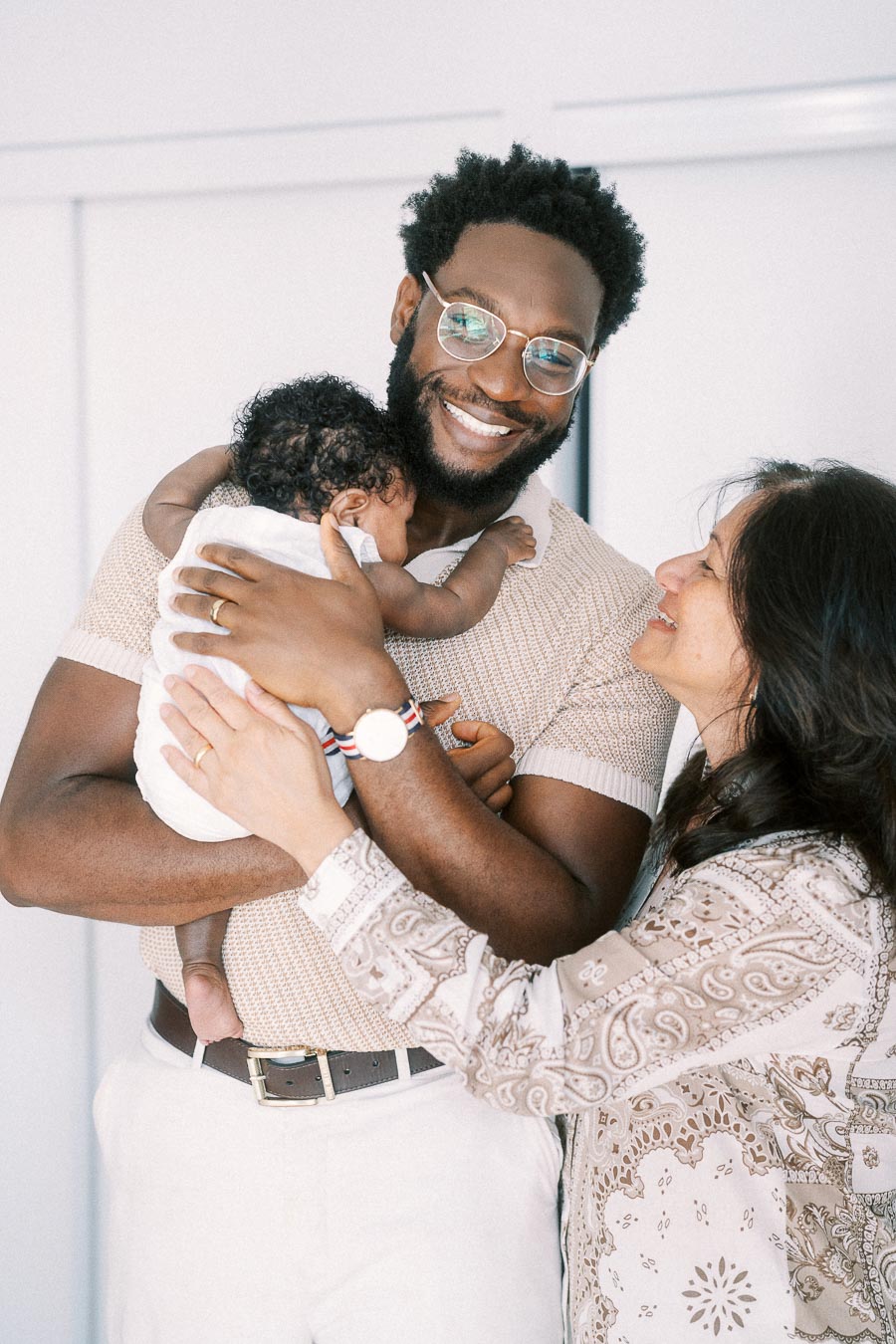 Terence holds baby Isabella while Karina smiles beside them at home.