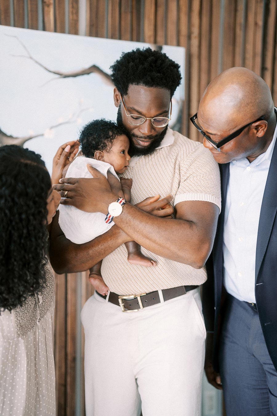 Father holding newborn daughter while family members gather close in a Toronto home.
