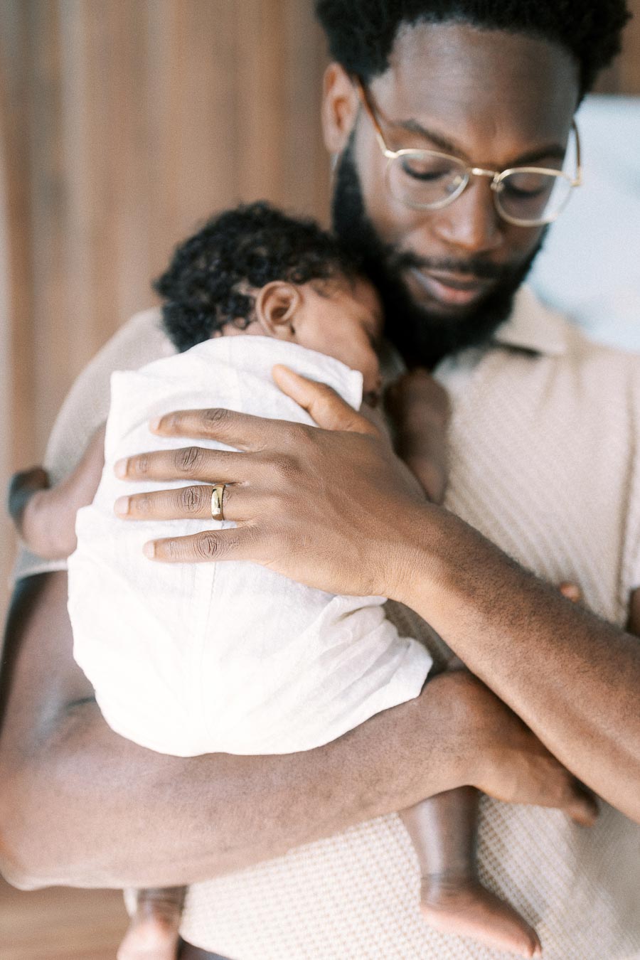 Father holding newborn daughter close against his chest at home