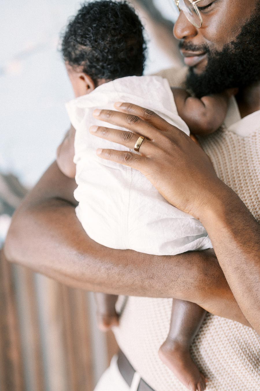 Father cradles his newborn daughter against his shoulder at home in Toronto.