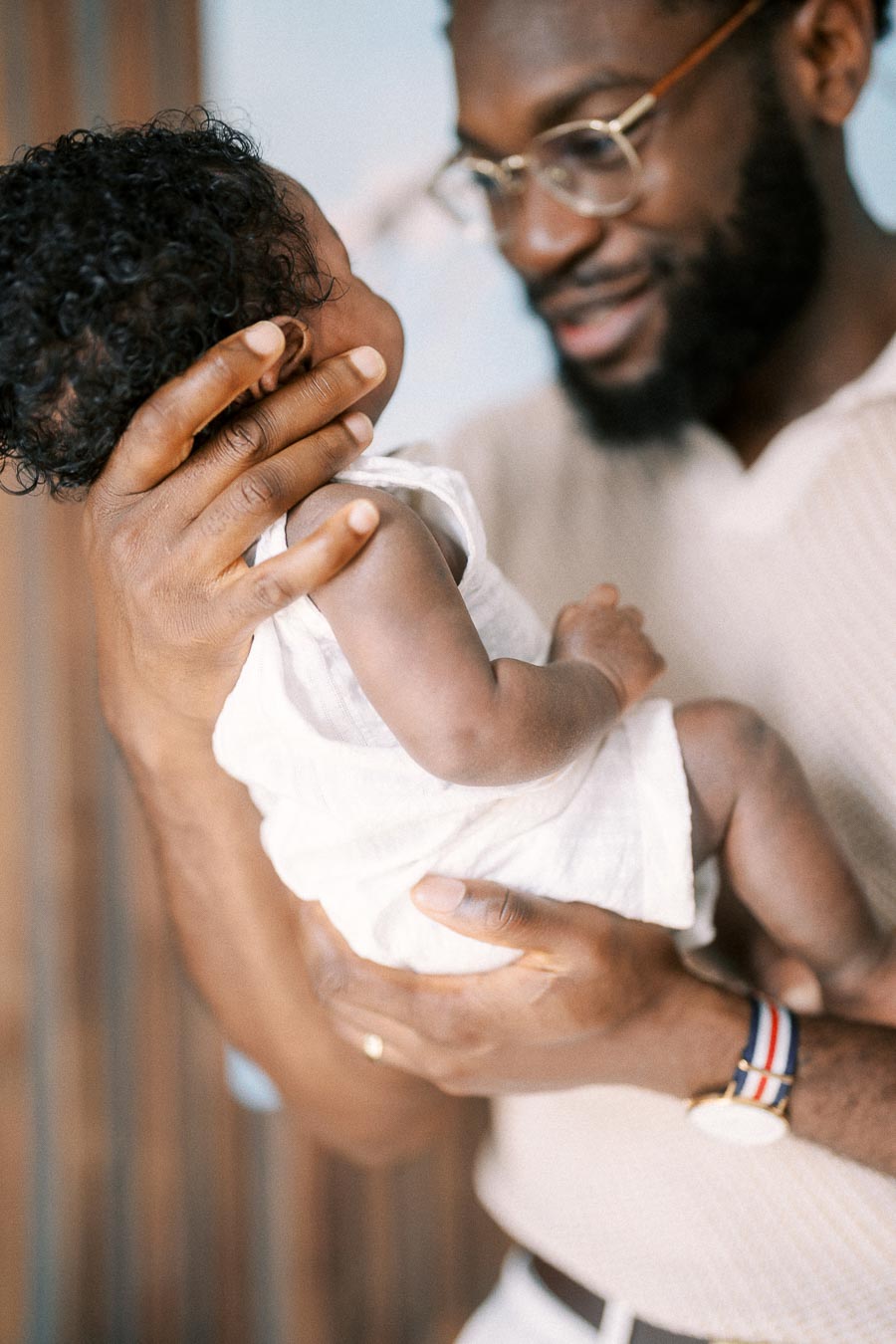 Terence gently cradles newborn Isabella against his chest at home.