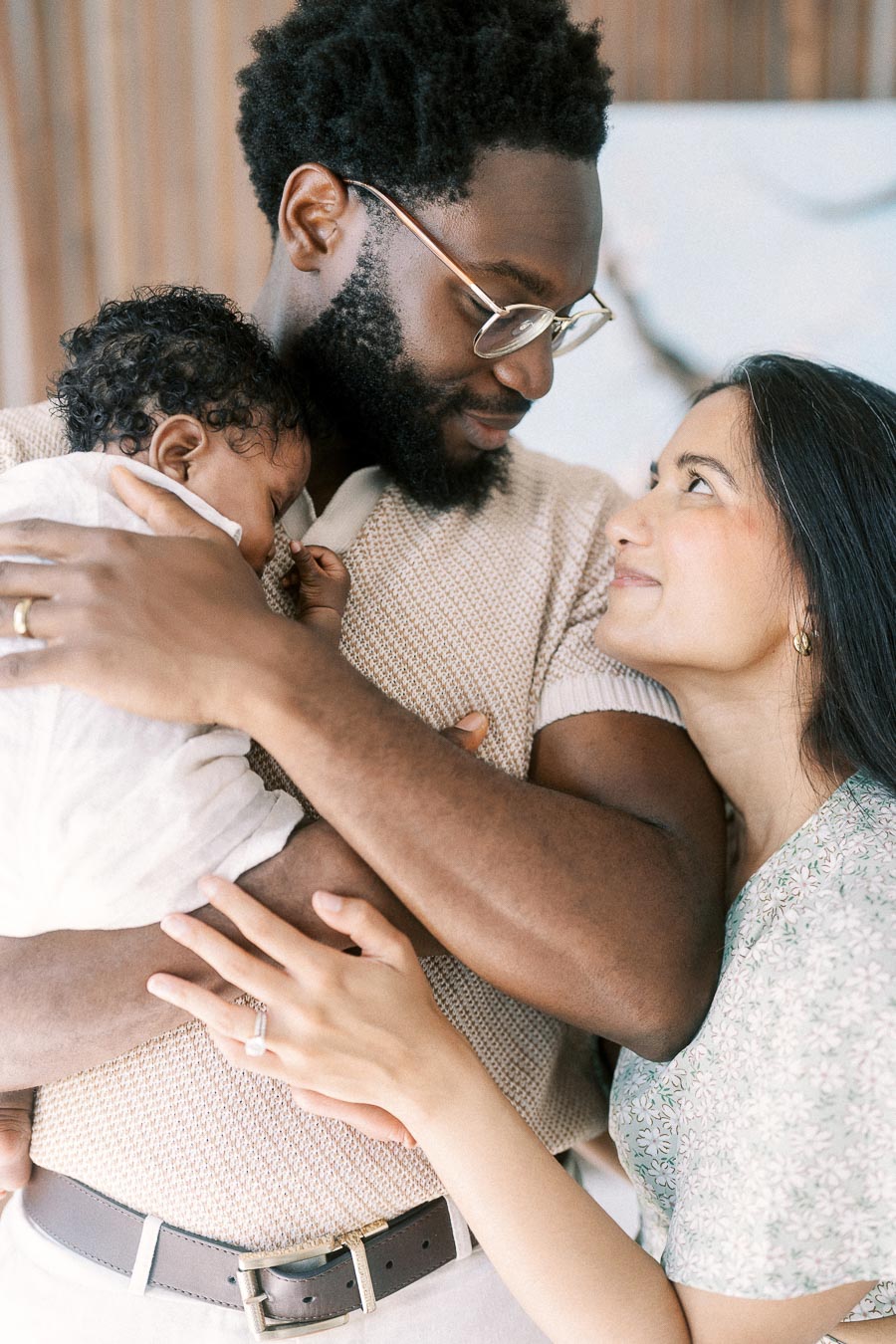 Terence holds newborn Isabella while Karina looks up at him at home.