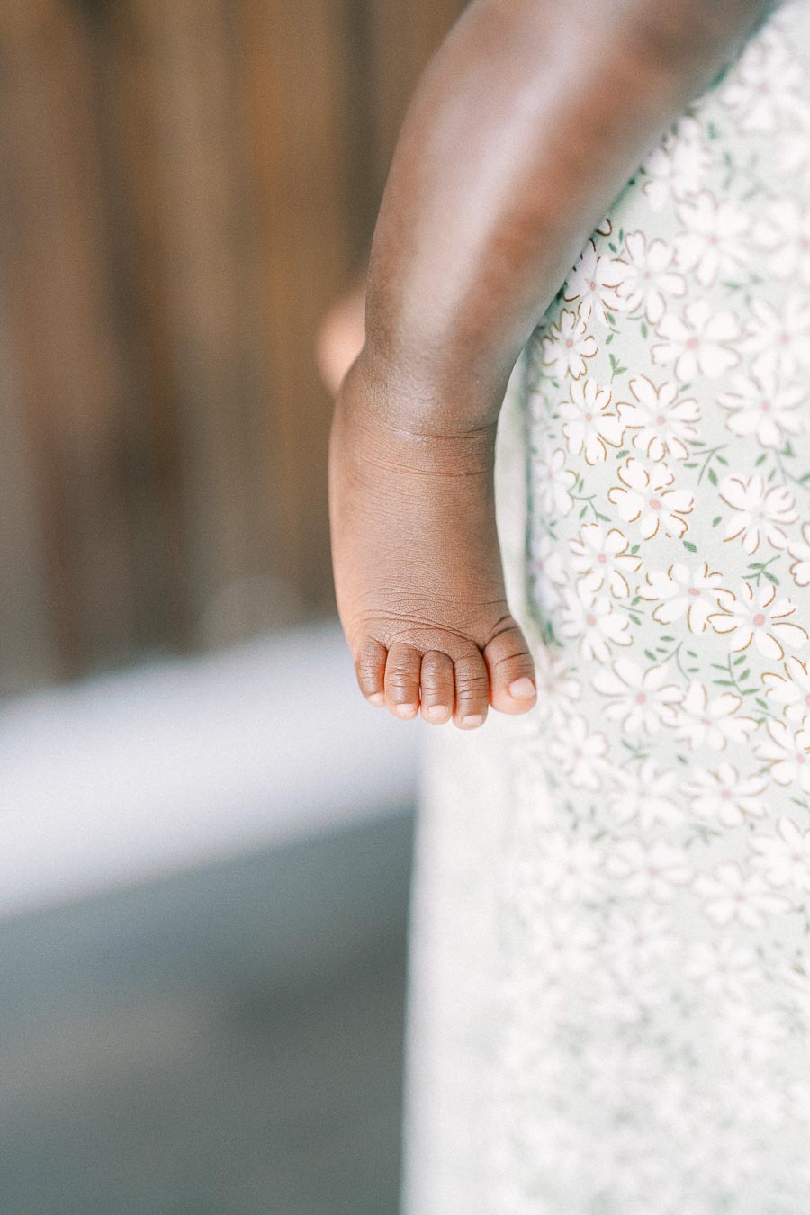 Isabella’s tiny foot rests against a white floral blanket at home.
