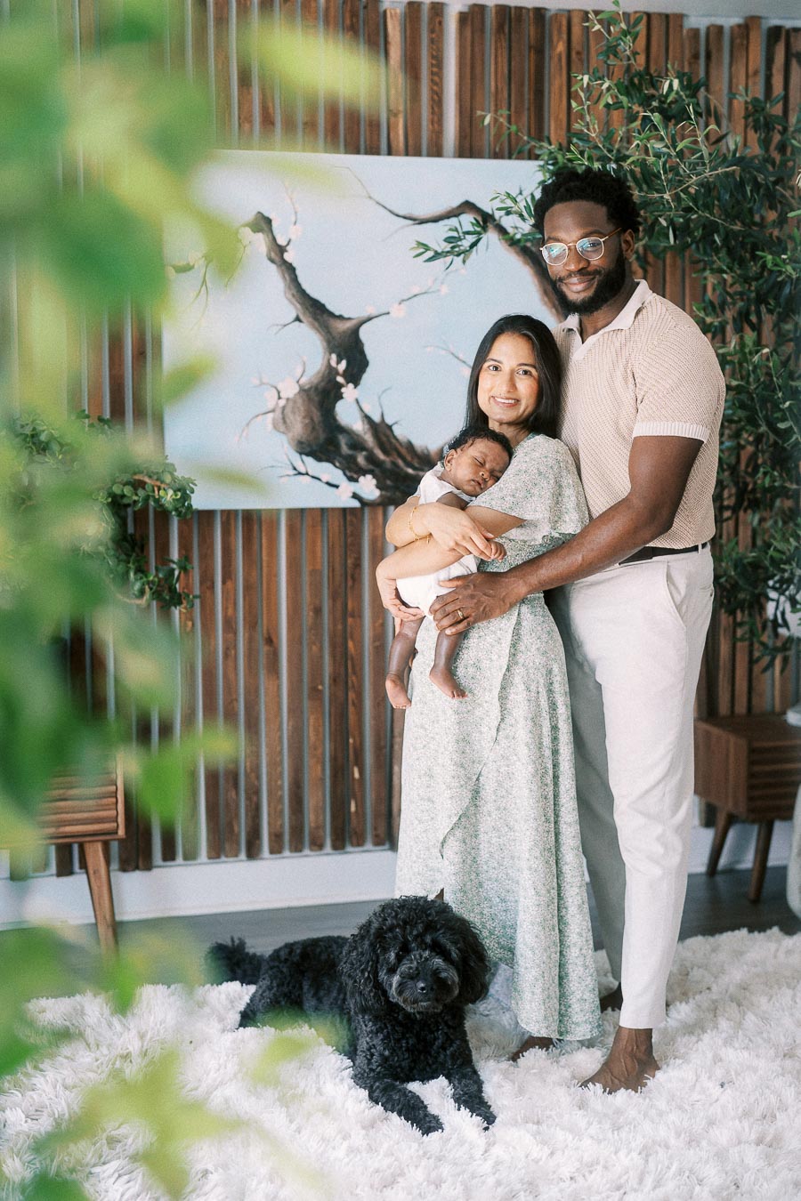 Karina and Terence hold newborn Isabella beside their black dog in their Toronto home.