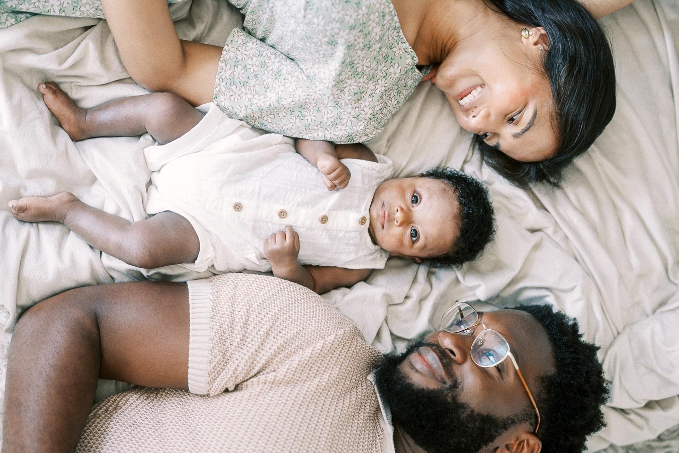 Karina and Terence lying on a bed with baby Isabella between them
