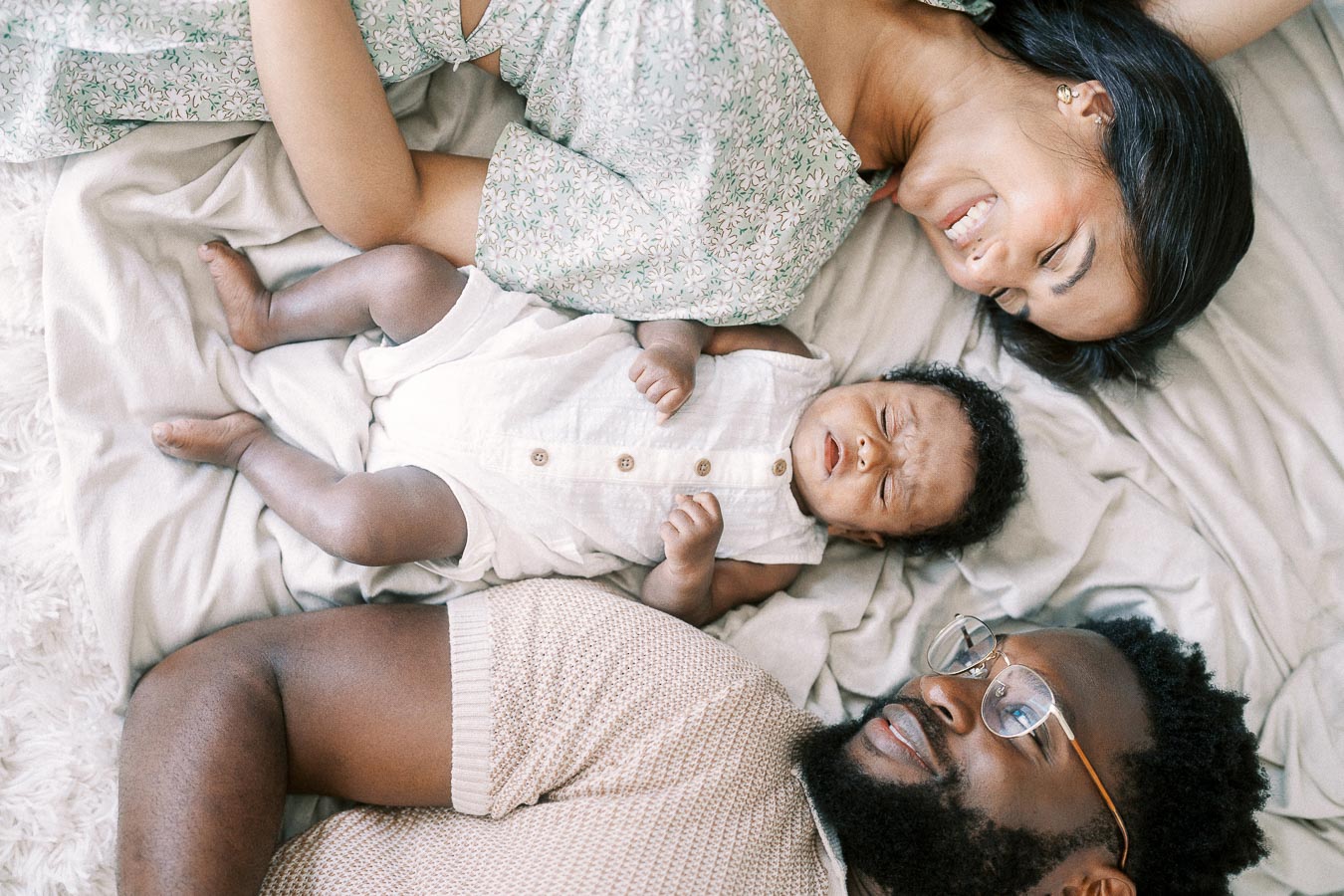 Karina and Terence lying on a bed beside newborn Isabella, who rests between them.