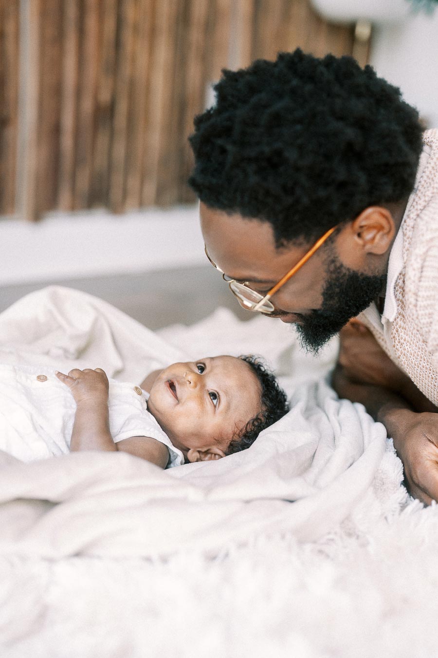 Terence leans close to newborn Isabella as she lies on a white blanket.