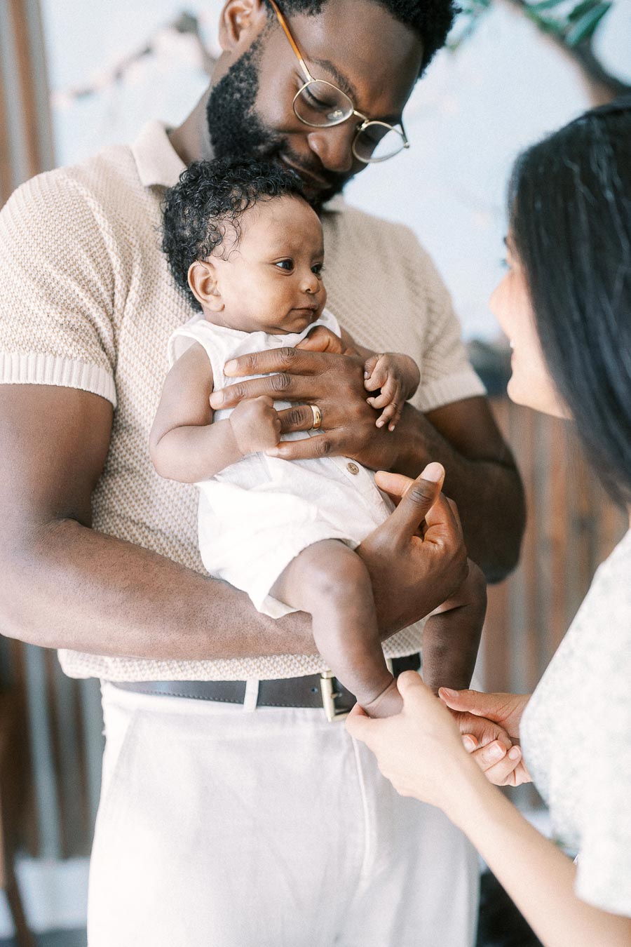Terence holds baby Isabella while Karina gently touches her foot at home in Toronto.