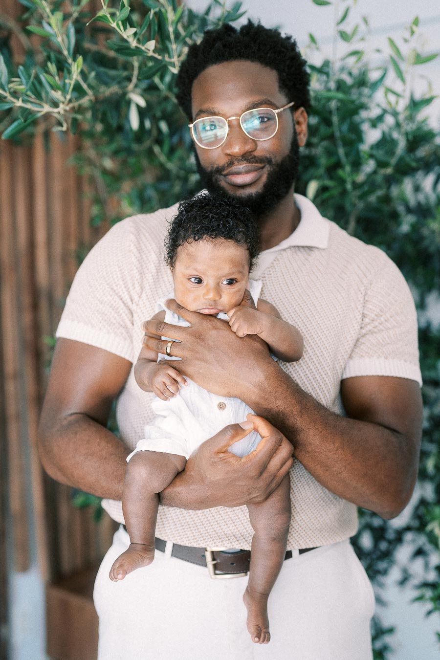 Terence holds baby Isabella against leafy greenery inside their Toronto home.