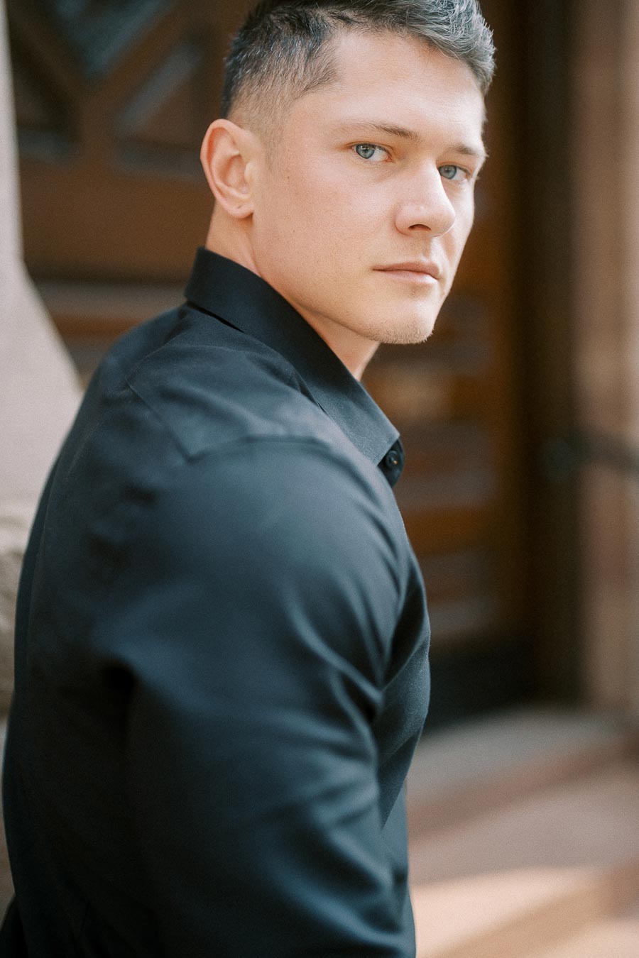 Groom-to-be in a black shirt looks back during a softly lit portrait in Toronto.