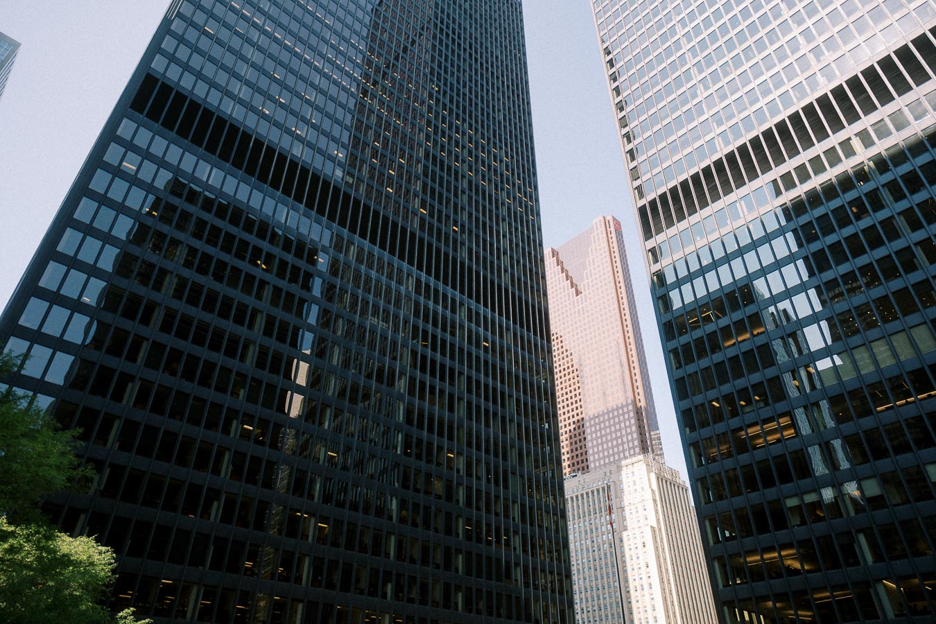 Tall glass office towers rise closely together in Toronto’s Financial District under clear evening light.