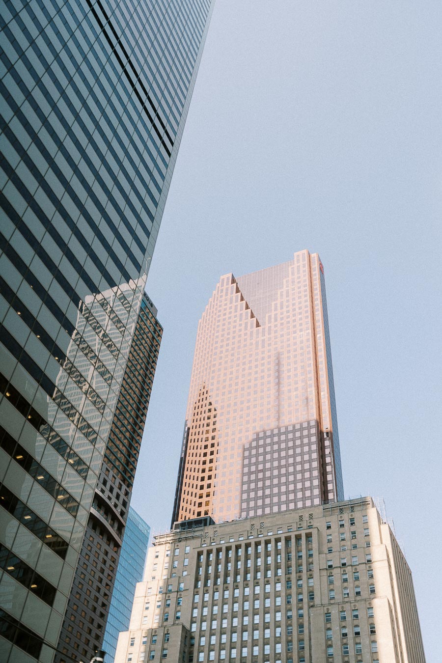 Downtown Toronto office towers rise against a pale sky with glass reflections and warm evening light.
