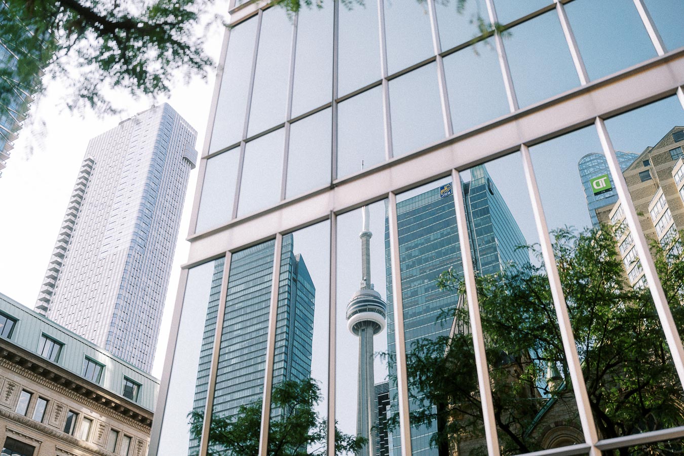 CN Tower and downtown Toronto skyscrapers reflected in a glass office building facade