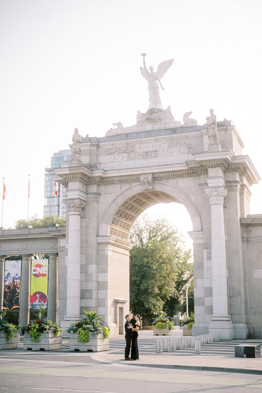 Couple embracing beneath the Princes' Gates arch at Exhibition Place in Toronto.