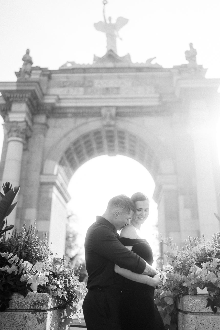 Couple embracing in black and white beneath the Princes' Gates arch at Exhibition Place.