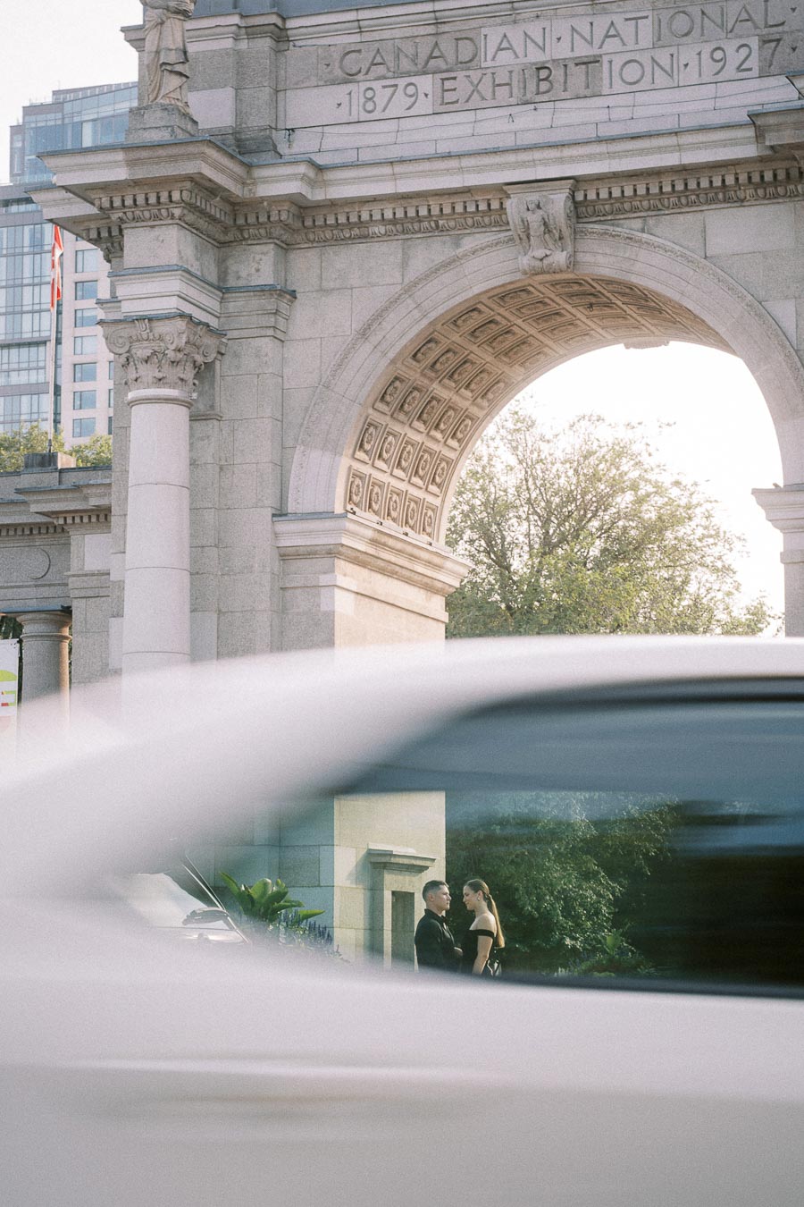 Couple seen through a passing car beneath the Canadian National Exhibition arch in Toronto.
