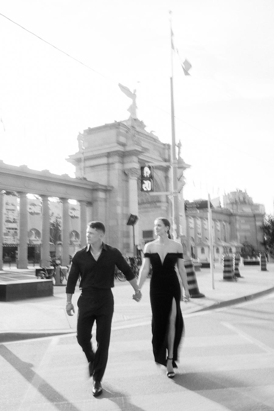 Couple holding hands while crossing near the Princes' Gates at Exhibition Place in Toronto.