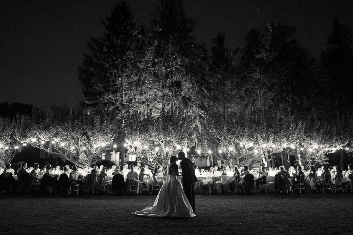 A black-and-white nighttime photograph of the bride and illuminated outdoor reception at Martin Estates.