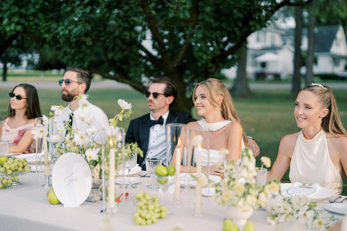 The newlyweds sit together at their outdoor reception table during a Martin Estates wedding in Niagara.