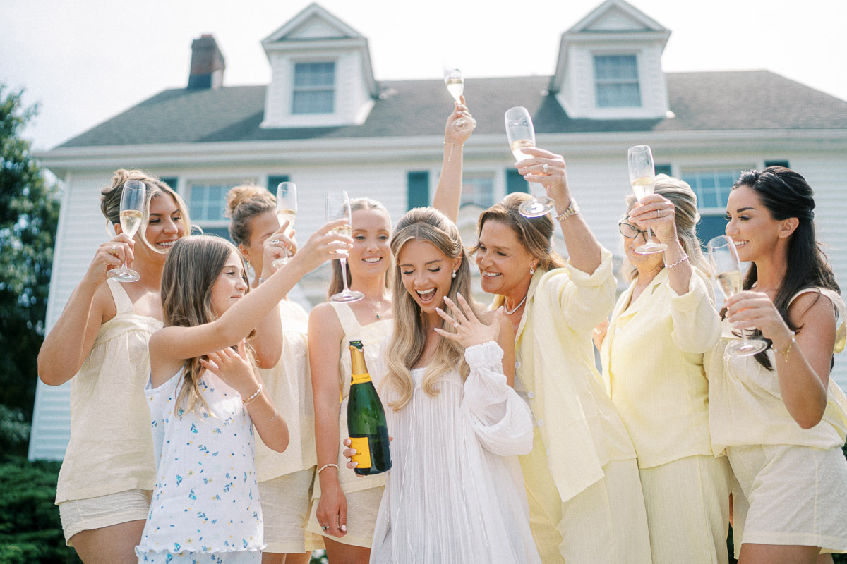 The bride and her wedding party celebrate with champagne outside the farmhouse at Martin Estates in Niagara.