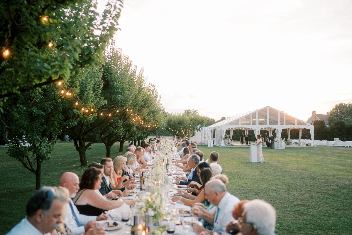 Guests share dinner at a long outdoor table as the sun sets over Martin Estates in Niagara.